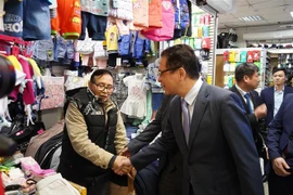 Đại sứ Đặng Minh Khôi hỏi thăm tình hình làm ăn buôn bán của bà con. (Ảnh: Duy Trinh/TTXVN)