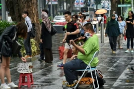 Du khách đi bộ trên phố thương mại Orchard ở Singapore. (Nguồn: AFP/TTXVN)