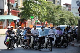 Người dân chen chân trong bóng mát khi chờ đèn xanh giao thông. (Ảnh: Quang Quyết/TTXVN)