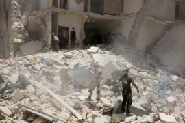 Lực lượng cứu hộ tìm kiếm người mắc kẹt trong đống đổ nát sau cuộc giao tranh ở Aleppo ngày 20/6. (Nguồn: AFP/TTXVN)