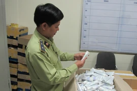 Cán bộ Đội Quảng lý thị trường số 15 đang kiểm tra lô mỹ phẩm nhập lậu vừa thu giữ trên địa bàn huyện Đan Phượng. (Ảnh: Đức Duy/Vietnam+)