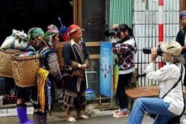 Du khách nước ngoài chụp ảnh đồng bảo dân tộc ở Sa Pa. (Ảnh: Thanh Hà/TTXVN)