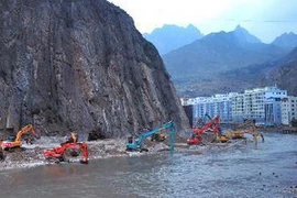 Nhân viên cứu nạn làm cạn nước đọng trong hồ rào chắn được tạo ra sau khi đất lở chặn sông Bạch Long. (Nguồn: XInhua)