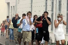 Khách du lịch đeo khẩu trang tránh khói bụi từ những đám cháy rừng sơ tán khỏi khu nghỉ mát Selce ở bờ biển Adriatic ngày 23/7. (Ảnh: AFP/TTXVN)