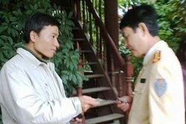 Quang Long đang xuất trình những giấy tờ chứng minh mình là phóng viên Báo Kinh tế nông thôn. (Nguồn: vietnamnet)