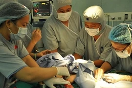 Các bác sỹ phẫu thuật tách rời cặp song sinh. (Ảnh: Phương Vy - TTXVN)