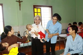 Linh mục Nguyễn Đăng Điền, giáo xứ Nhân hòa, huyện Nghi Lộc, tỉnh Nghệ An bế cháu bé khuyết tật tại Trung tâm nuôi dưỡng trẻ em mồ côi và khuyết tật 19/3. (Ảnh: TTXVN phát)