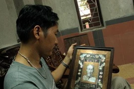 Nghệ nhân trẻ Nguyễn Đình Vinh bên 1 tác phẩm chân dung Bác. (Nguồn: Internet)