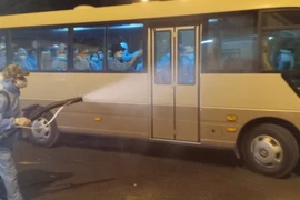 Phun thuốc diệt khuẩn đoàn xe khi từ sân bay Cần Thơ về đến khu các ly. (Ảnh: Huỳnh Phúc Hậu/TTXVN)