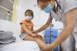 Bác sỹ khám cho bệnh nhi sốt xuất huyết tại bệnh viện Thanh Nhàn. (Ảnh: Minh Quyết/TTXVN)