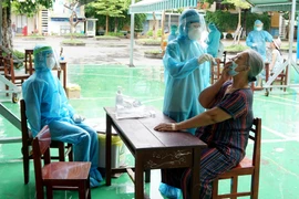 Lấy mẫu sinh phẩm của người dân vùng phong tỏa tại Đà Nẵng để xét nghiệm SARS-CoV-2. (Ảnh: TTXVN phát)