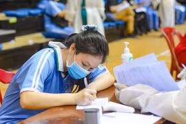 Học sinh viết vào phiếu cam kết tiêm chủng. (Ảnh: Văn Dũng/TTXVN)