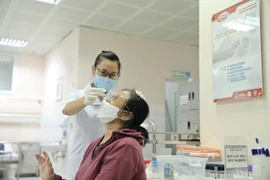 Nhân viên y tế lấy mẫu xét nghiệm cho người dân tới khám. (Ảnh: TTXVN/Vietnam+)