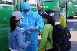 Hỗ trợ người dân khai báo y tế trước khi lên xe về Quảng Ngãi. (Ảnh: Trần Lê Lâm/TTXVN)