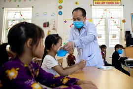 Cán bộ y tế phát khẩu trang cho các em học sinh tại Trường Phổ thông dân tộc bán trú Tiểu học xã Khâu Vai (Mèo Vạc, Hà Giang). (Ảnh: Nam Thái/TTXVN)