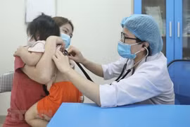 Bác sỹ Bệnh viện Bệnh nhiệt đới Trung ương khám cho bệnh nhi xuất hiện triệu chứng cúm A. (Ảnh: Minh Quyết/TTXVN)