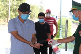 Người dân phải đeo khẩu trang, đo nhiệt độ và sát khuẩn tay để phòng dịch. (Ảnh: Sỹ Tuyên/TTXVN) 