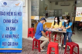 Nhân viên bảo hiểm xã hội tư vấn về chính sách bảo hiểm xã hội, bảo hiểm y tế cho người dân. (Ảnh: TTXVN/Vietnam+)