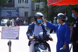 Đo thân nhiệt cho người dân. (Ảnh: Minh Quyết/TTXVN)