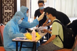 Nhân viên y tế hướng dẫn chuyên gia, lao động nước ngoài khai báo y tế và kiểm tra thân nhiệt trước khi vào khách sạn cách ly. (Ảnh: Đồng Thúy/TTXVN)