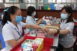 Nhân viên y tế chuẩn bị thuốc để cấp cho bệnh nhân điều trị ngoại trú có tham gia bảo hiểm y tế. (Ảnh: Xuân Triệu/TTXVN)