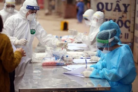 Nhân viên y tế làm công tác lấy mẫu xét nghiệm COVID-19. (Ảnh: TTXVN/Vietnam+)