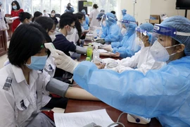 Khám sàng lọc cho học sinh trước khi tiêm vaccine. (Ảnh: TTXVN/vietnam+)