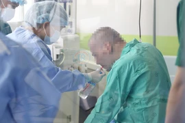 Bệnh nhân 91 đã ngồi dậy, ăn uống với sự hỗ trợ của nhân viên y tế. (Ảnh: TTXVN phát)