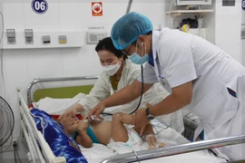 Bác sỹ thăm khám cho bệnh nhi mắc tay chân miệng. (Ảnh: Phan Sáu/TTXVN)