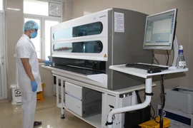 Cán bộ y tế xét nghiệm mẫu trên máy xét nghiệm Real time PCR. (Ảnh: TTXVN) 