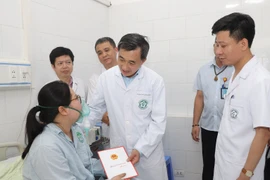 Thứ trưởng Bộ Y tế Trần Văn Thuấn đã thăm hỏi, tặng quà động viên nạn nhân trong vụ cháy ở Trung Kính. (Ảnh: PV/Vietnam+)