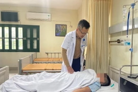 Thạc sỹ Nguyễn Duy Khánh thăm khám cho bệnh nhân. (Ảnh: PV/Vietnam+)