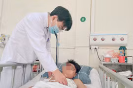 Phó giáo sư Phùng Duy Hồng Sơn thăm khám cho bệnh nhân sau phẫu thuật. (Ảnh: PV/Vietnam+)