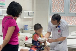 Bác sĩ Nguyễn Đức Lân - Trưởng khoa Ngoại nhi tổng hợp thăm khám cho bệnh nhi C. trước khi xuất viện. (Ảnh: PV/Vietnam+) 