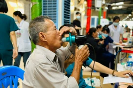 Người dân đo chức năng hô hấp để khám và điều trị bệnh phổi tắc nghẽn mạn tính. (Ảnh: T.G/Vietnam+)