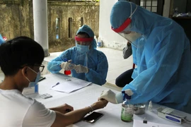 Các cán bộ y tế tiến hành xét nghiệm nhanh COVID-19 cho người dân trở về từ vùng có dịch. (Ảnh: Hồ Cầu/TTXVN)