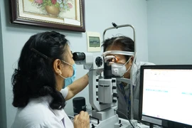 Khám, kiểm tra mắt cho bệnh nhân. (Ảnh: PV/Vietnam+)