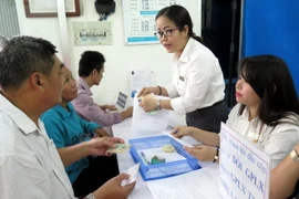 Người dân đến làm thủ tục cấp đổi và nhận giấy phép lái xe tại Bưu điện Bình Chánh. (Ảnh: Hoàng Hải/Vietnam+)