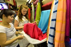 Khách du lịch tham quan và chọn mua sản phẩm lụa Vạn Phúc. (Ảnh: Thanh Hà/TTXVN)