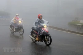 Người dân thị xã Sapa mặc áo mưa tránh rét. (Ảnh: Quốc Khánh/TTXVN)