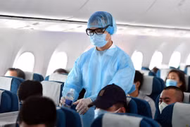 Tiếp viên Vietnam Airlines mặc đồ bảo hộ y tế trên chuyến bay để phòng chống dịch COVID-19. (Ảnh: CTV/Vietnam+)