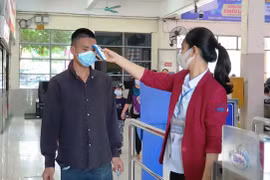 Nhân viên bến xe Giáp Bát kiểm tra thân nhiệt hành khách trước khi ra ôtô để về quê dịp nghỉ 30/4. (Ảnh: Việt Hùng/Vietnam+)
