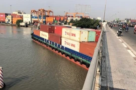 Tàu Phước Long 72 chở container số hiệu SG9838 trọng tải 4.600 tấn bị mắc kẹt dưới cầu Đồng Nai sáng 12/4, trước khi được cứu hộ và lai dắt đến nơi an toàn. (Ảnh: TTXVN phát)