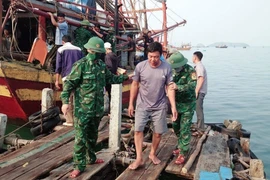 Lực lượng Bộ đội Biên phòng tỉnh Quảng Bình đưa các ngư dân bị nạn trên biển vào bờ. (Ảnh: TTXVN phát)
