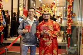 Khách hàng vui vẻ khi mua được vàng trong ngày vía Thần Tài. (Ảnh: Đức Duy/Vietnam+)