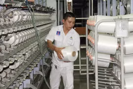 Công nhân kỹ thuật xưởng Filament - NMXS Đình Vũ đứng máy sản xuất sợi DTY. (Ảnh: Đức Duy/Vietnam+)