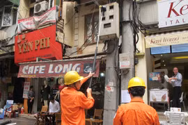 Nhân viên ngành điện đang chốt chỉ số công tơ của khách hàng. (Ảnh: Đức Duy/Vietnam+)