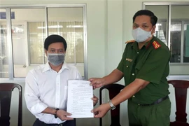 Lãnh đạo Công an huyện Châu Thành trao Quyết định xử phạt Lương y Hà Hoàng Vũ. (Ảnh: Trung Hiếu/TTXVN)