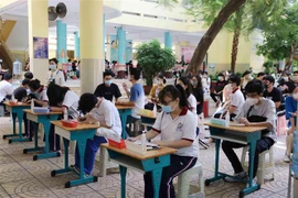 Học sinh ngồi giãn cách tại khu vực điền thông tin cá nhân trước khi vào lấy mẫu tại điểm Trường Tiểu học Nguyễn Bỉnh Khiêm (Quận 1). (Ảnh: Thu Hương/TTXVN)