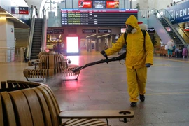 Nhân viên phun thuốc khử trùng nhằm ngăn chặn sự lây nhiễm của dịch COVID-19 tại nhà ga ở Moskva, Nga. (Ảnh: AFP/TTXVN)